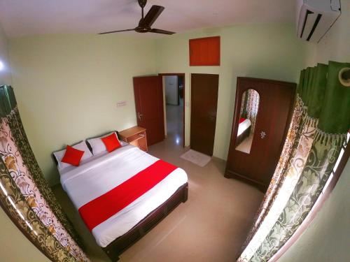 een slaapkamer met een bed met rode kussens en een spiegel bij Shalom Palace in Cochin