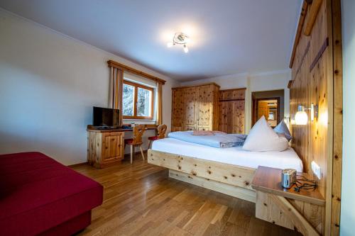 a bedroom with a bed and a desk in a room at Hotel Raunig in Bad Kleinkirchheim