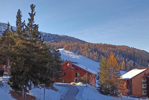 un edificio rojo en la nieve junto a una montaña en T3 avec terrasse 6 personnes, La Joue du Loup, en La Joue du Loup