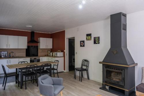 cocina y sala de estar con mesa y chimenea en La Grange du Héron, en Balaguier-dʼOlt