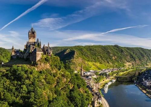 a castle on a hill next to a river at Ferienwohnung Sternenstube in Völkenroth