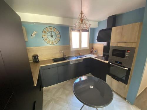 une cuisine avec une horloge sur le mur et une table dans l'établissement Magnifique villa moderne Jacuzzi 4 chambres 3 salle de bain proche plage centre ville activité, au Barcarès