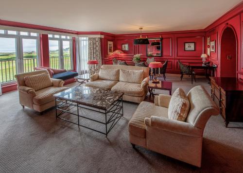 a living room with red walls and couches and a table at Old Course Hotel St Andrews in St. Andrews