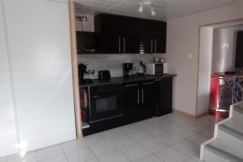 une cuisine avec des armoires noires et un comptoir noir dans l'établissement Gite Glaïeul, à Celles-sur-Plaine