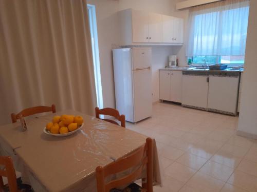 a kitchen with a table with a bowl of oranges on it at Sunset View Appartment (Thanasis 3) in Kalavárda