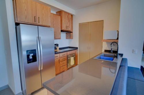 a kitchen with wooden cabinets and a stainless steel refrigerator at Best Apt Luxury Modern New 2BR Gym Pool 3mins SPGG in Monterrey
