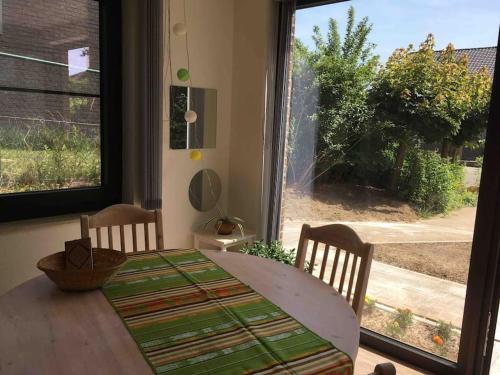 a dining room table with a view of a yard at 'het T-huisje' volledig ingerichte studio in Leuven