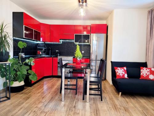 a kitchen with red cabinets and a table and a couch at HAFCIK Apartamenty in Poronin