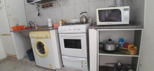 a kitchen with a microwave and a washing machine at Departamentos La Tita in Concepción del Uruguay