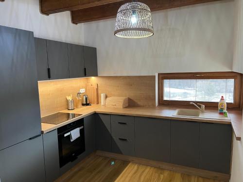 eine Küche mit grauen Schränken, einem Waschbecken und einem Fenster in der Unterkunft Mytho 2 in Mýto pod Ďumbierom