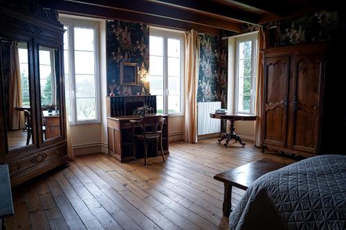 een slaapkamer met houten vloeren en ramen en een bureau bij Suite parentale de luxe in Rouffignac