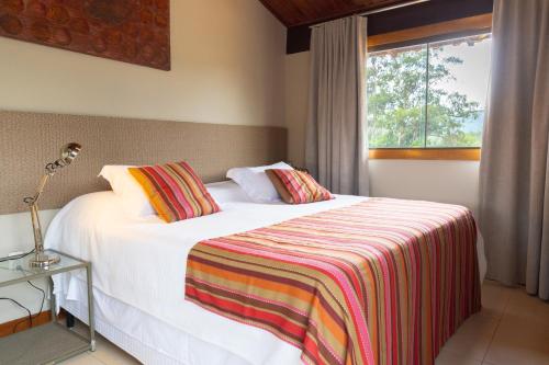 a bedroom with a white bed with a striped blanket at Casa da Lua Pousada in Alto Paraíso de Goiás