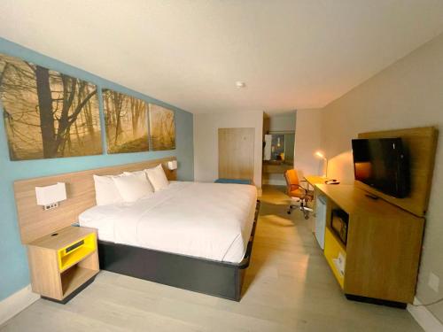 um quarto de hotel com uma cama e uma televisão em Days Inn by Wyndham Raleigh Glenwood-Crabtree em Raleigh