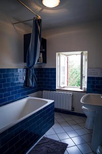 La salle de bains est pourvue de carrelage bleu, d'une baignoire et d'un lavabo. dans l'établissement Chambre familiale 5 personnes, à Rouffignac