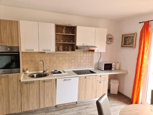 a kitchen with white cabinets and a sink at Apartman Branka in Povljana
