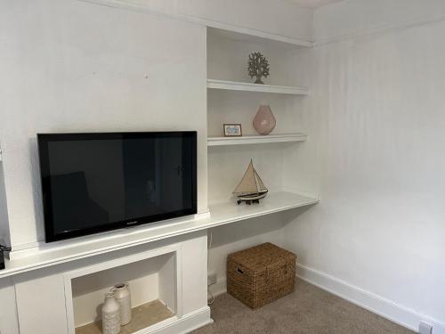 a flat screen tv sitting on top of a fireplace at Charming house by the sea in Ryde