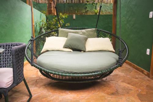 a wicker swing chair with pillows on a porch at Casa da Lua Pousada in Alto Paraíso de Goiás