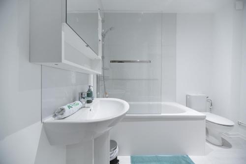 a white bathroom with a sink and a bath tub at ※Perrier Fraise※ Coeur de ville ⁕ Appt d'exception in Clermont-Ferrand