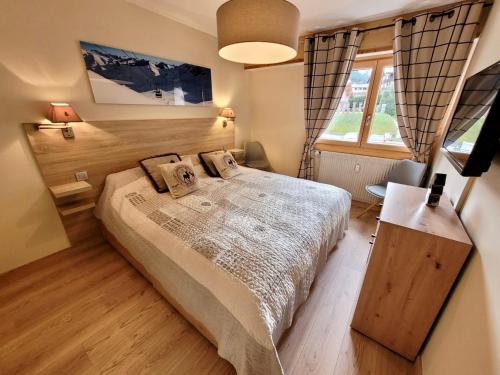 une chambre avec un grand lit et une fenêtre dans l'établissement Appartement T3 rénové, centre Les Gets, proche pistes, 6 pers, balcon, parking, équipements complets - FR-1-598-30, aux Gets