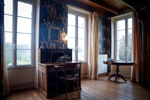 um quarto com uma mesa, cadeiras e janelas em Chambre confortable dans maison bourgeoise em Rouffignac