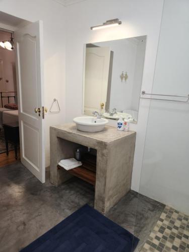 La salle de bains est pourvue d'un lavabo et d'un miroir. dans l'établissement Die Dorpshuis Graaff Reinet, à Graaff-Reinet