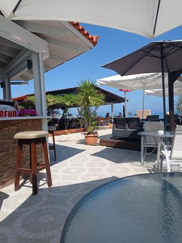 a patio with a pool and umbrellas and a table and chairs at Ninos On The Beach Hotel in Roda
