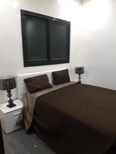 ein Schlafzimmer mit einem Bett mit zwei Lampen und einem Fenster in der Unterkunft Résidence Edelweiss in Dakar