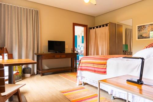 a bedroom with a bed and a desk with a television at Casa da Lua Pousada in Alto Paraíso de Goiás