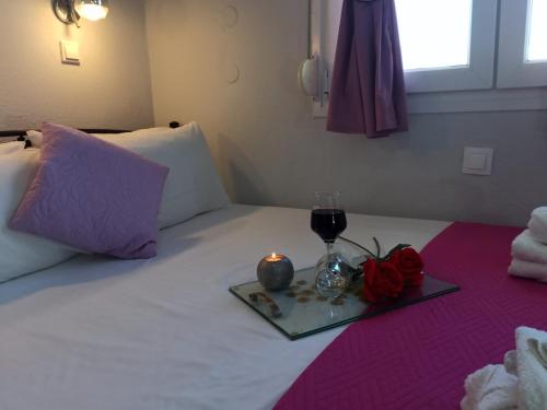 a tray with a glass of wine and a candle on a bed at Central Fountain in Asprovalta