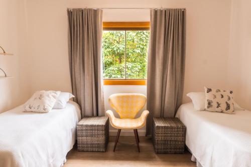 a room with two beds and a chair and a window at Casa da Lua Pousada in Alto Paraíso de Goiás