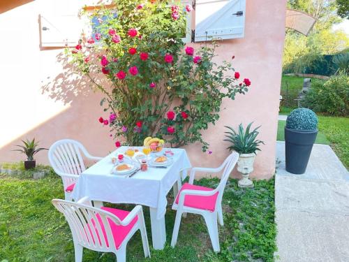 une table blanche avec des chaises roses dans un jardin dans l'établissement Casa Luciana, à Saint-Priest