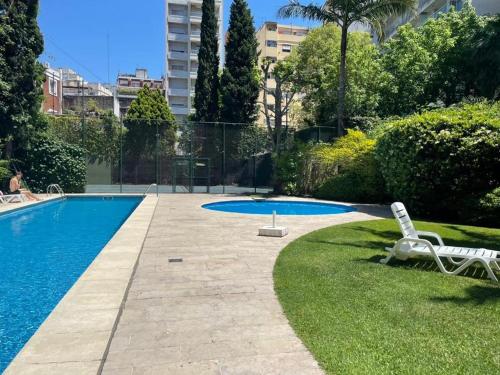 una piscina con 2 sillas de jardín junto a ella en Palermo Soho. 3 ambientes con piscina y cochera en Buenos Aires