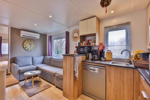 a kitchen and a living room with a couch at Grand Mobil Home 6 personnes climatisé avec 3 chambres et 2 salles de bains à Munster en Alsace in Munster