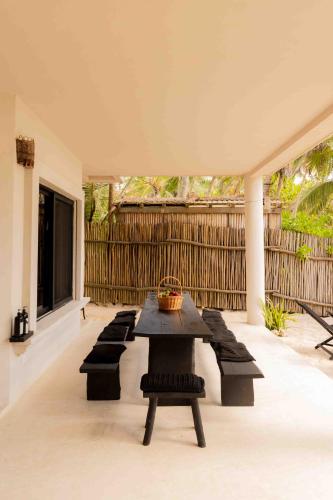 a patio with a table and benches and a fence at NEST Tulum in Tulum
