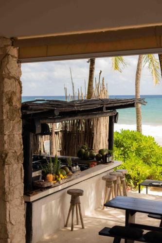 a bar with stools and a view of the beach at NEST Tulum in Tulum