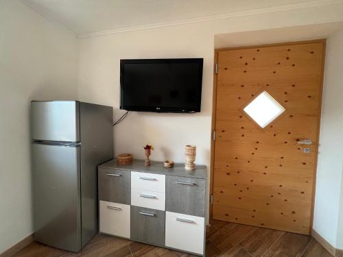 a room with a refrigerator and a television on the wall at Appartamento Sara in Commezzadura