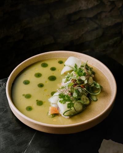 a bowl of soup with green peas and cheese at NEST Tulum in Tulum