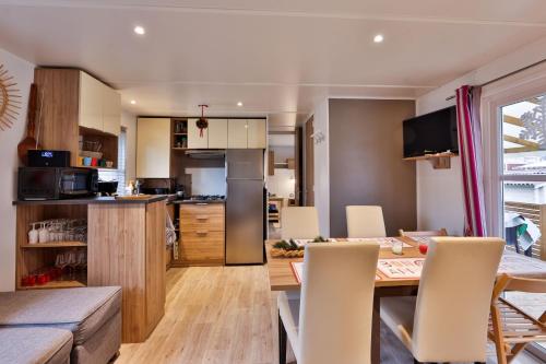 a kitchen and dining room with a table and chairs at Grand Mobil Home 6 personnes climatisé avec 3 chambres et 2 salles de bains à Munster en Alsace in Munster