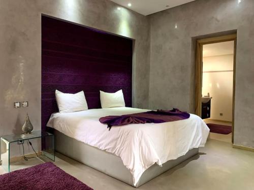 a bedroom with a large bed with a purple headboard at Villa Coty Palmeraie in Marrakesh