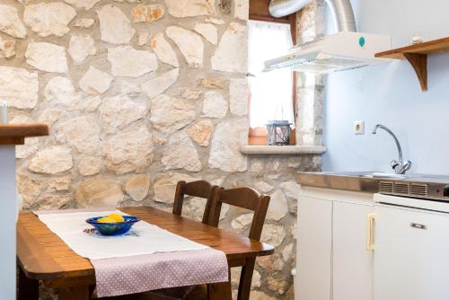 eine Küche mit einem Holztisch und einer Steinmauer in der Unterkunft Abeloklima country house in Vasilikos