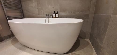 un bagno con vasca e 2 bottiglie di vino di The Beautiful Bankmore Penthouse a Belfast