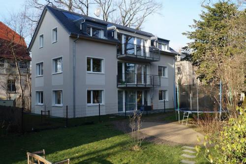 una gran casa blanca con un parque infantil delante de ella en Stilvolle Wohnung in Elbnähe mit Balkon, Parkplatz, en Dresden
