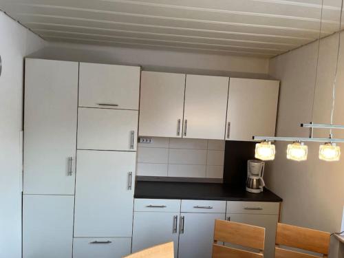a kitchen with white cabinets and a table and chairs at Ferienwohnung in ruhiger Lage in Thurnau