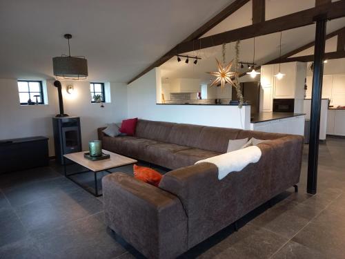 sala de estar con sofá marrón y cocina en Op 't Roth 12 ruime sfeervolle vakantiewoning in 't groen, en Oudenaarde