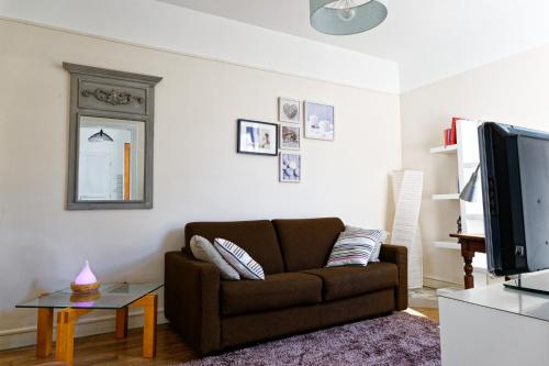 a living room with a brown couch and a tv at Les Tournelles in Courbevoie