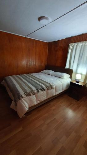 a bedroom with a bed with a wooden wall at Hostal El Baltico in Castro