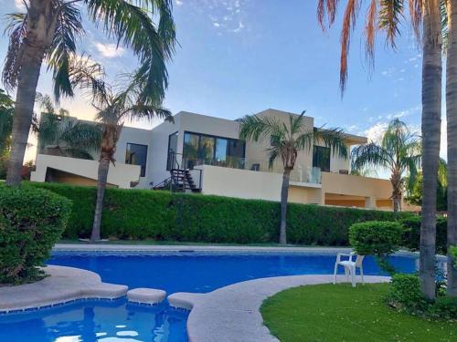 a house with palm trees and a swimming pool at Hermosa residencia de lujo in Hermosillo