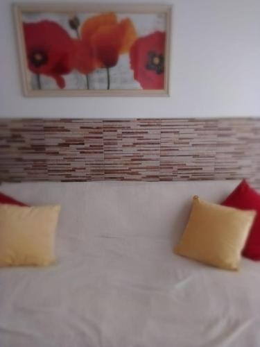 1 cama con almohadas rojas y una pintura en la pared en Departamento Isabel II en Mar del Plata
