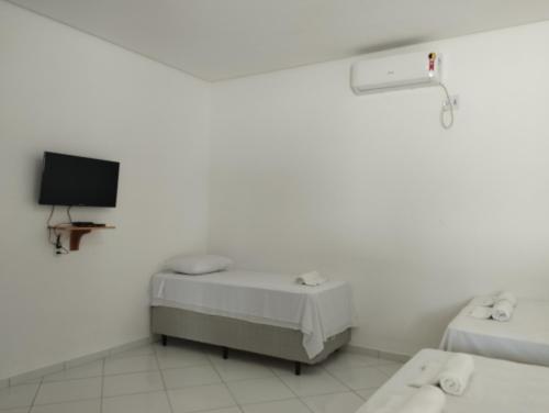 a white room with two beds and a tv at Pousada Casa Grande in Barreirinhas