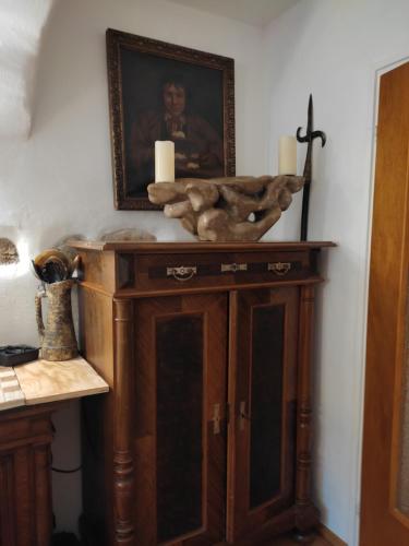 a wooden cabinet with two candles and a picture on the wall at Künstlerhaus Weissgerbergütl in Marquartstein